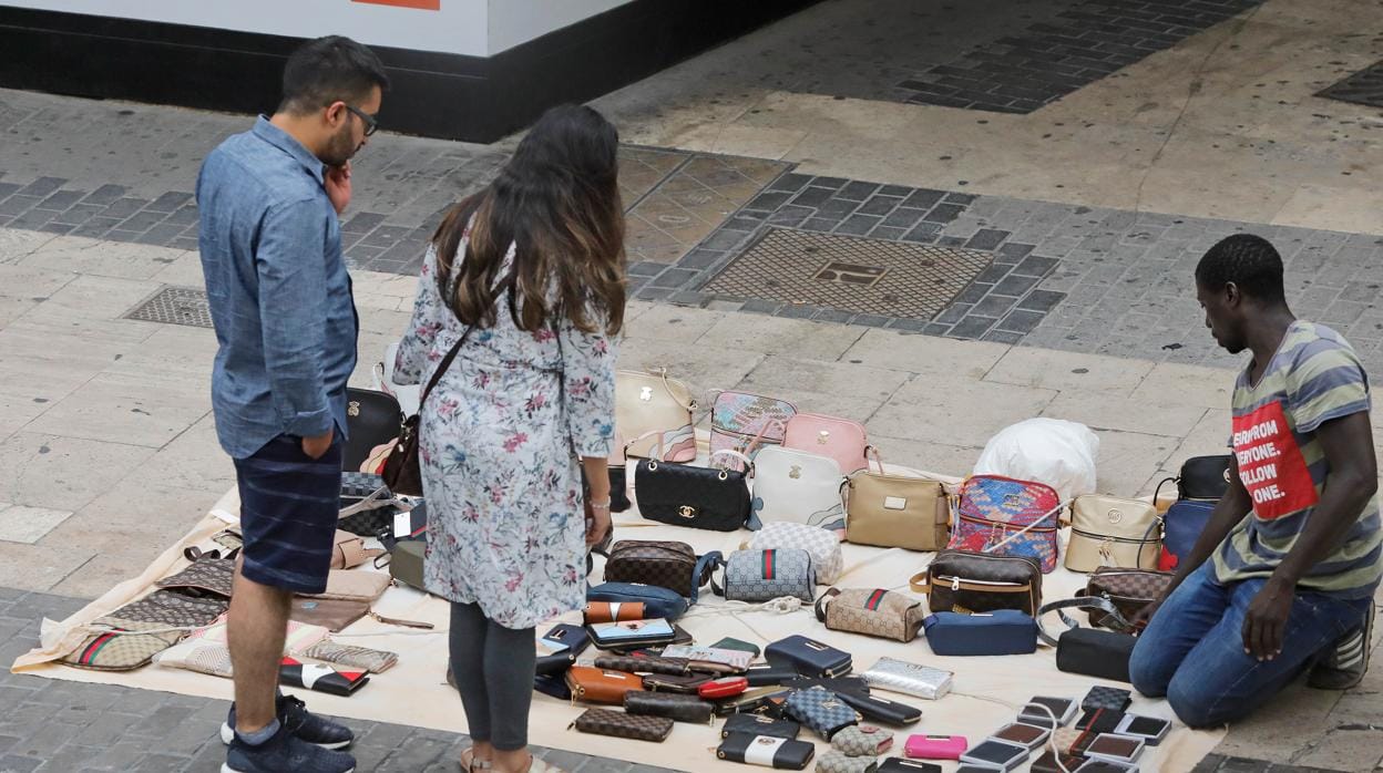 Turistas con un vendedor en una calle de Valencia