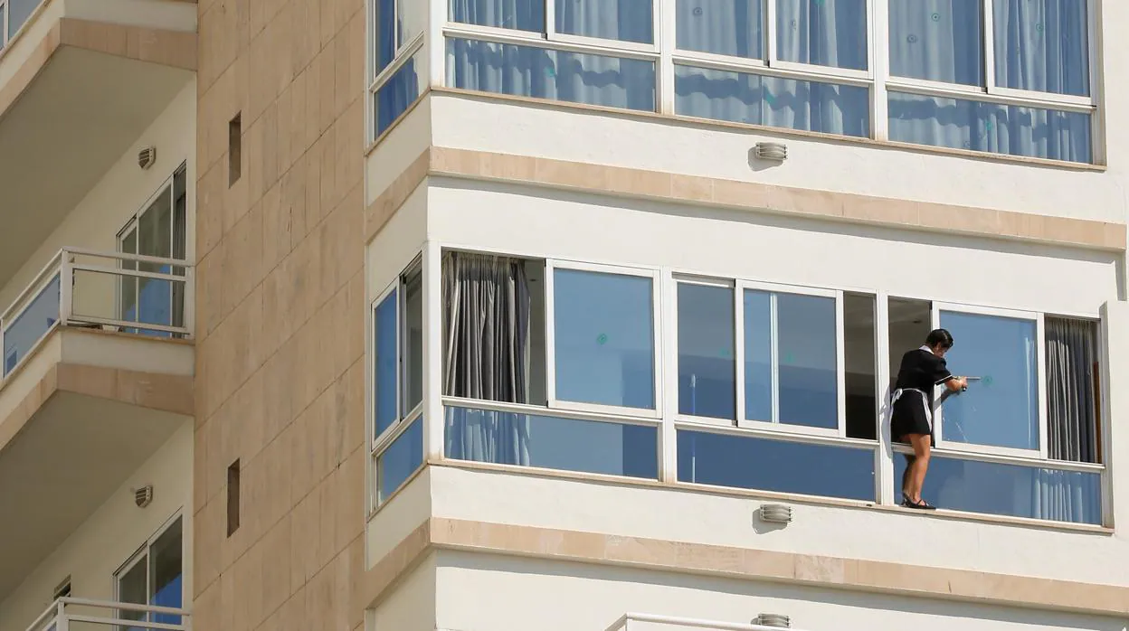 Una empleada del servicio de limpieza limpia la ventana de un hotel en Palma de Mallorca