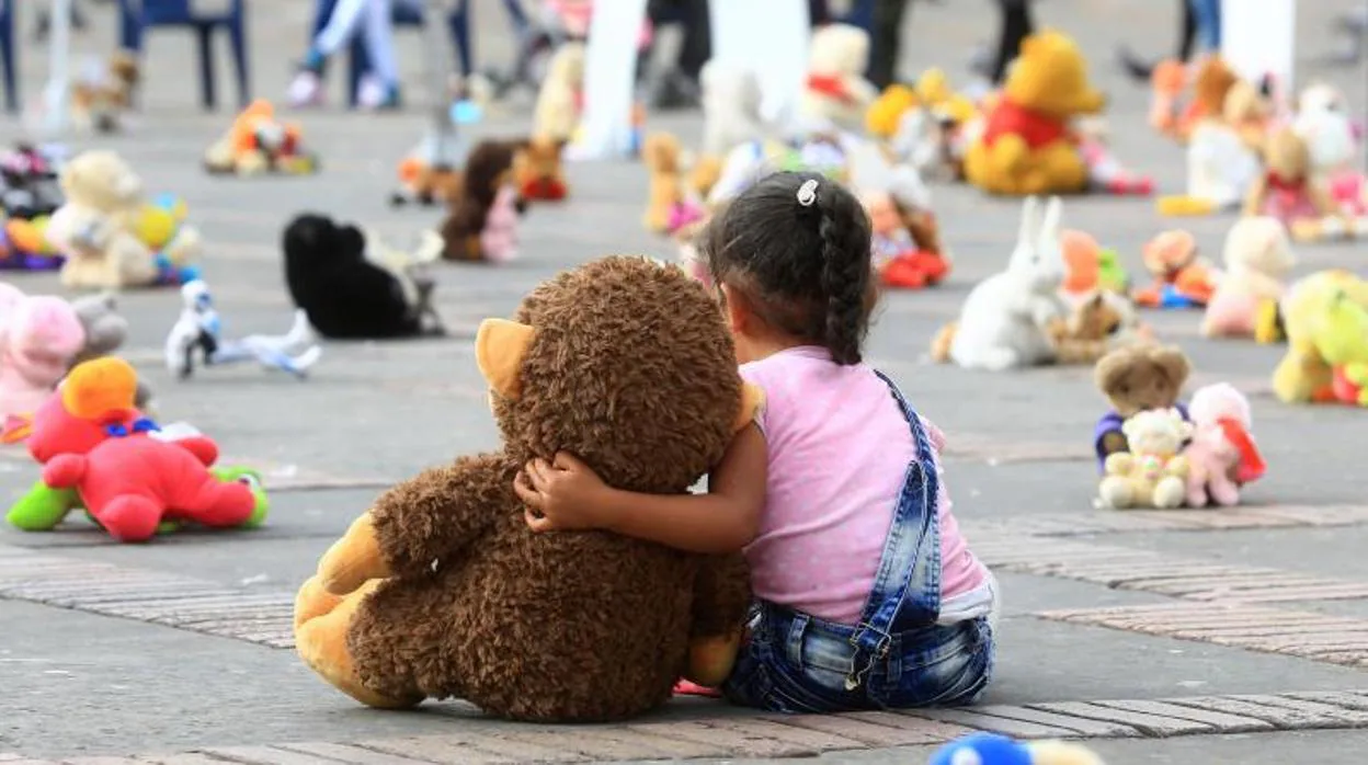 Una niña abraza un muñeco durante un "plantón de juguetes" organizado por Aldeas Infantiles