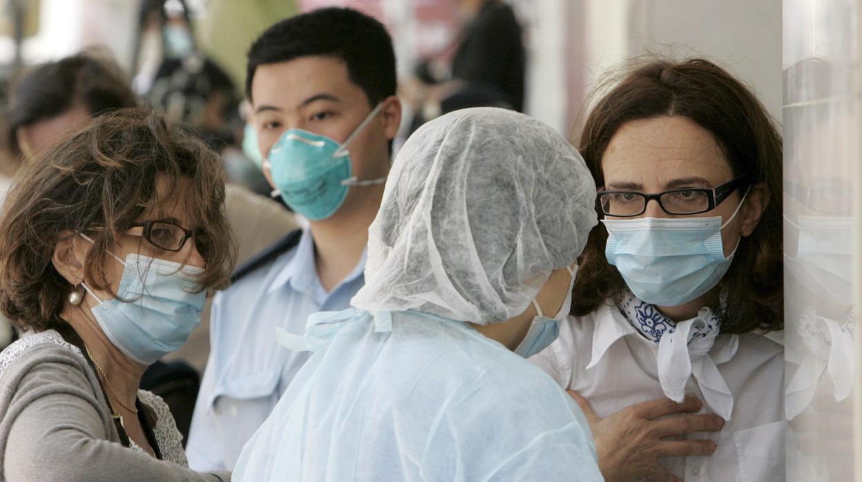 Imagen de archivo con varios turistas y personal médico con mascarillas en China, donde un huésped mexicano dio positivo por gripe A