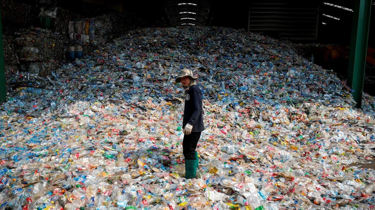 Un trabajador de un vertedero, rodeado de botellas de plástico