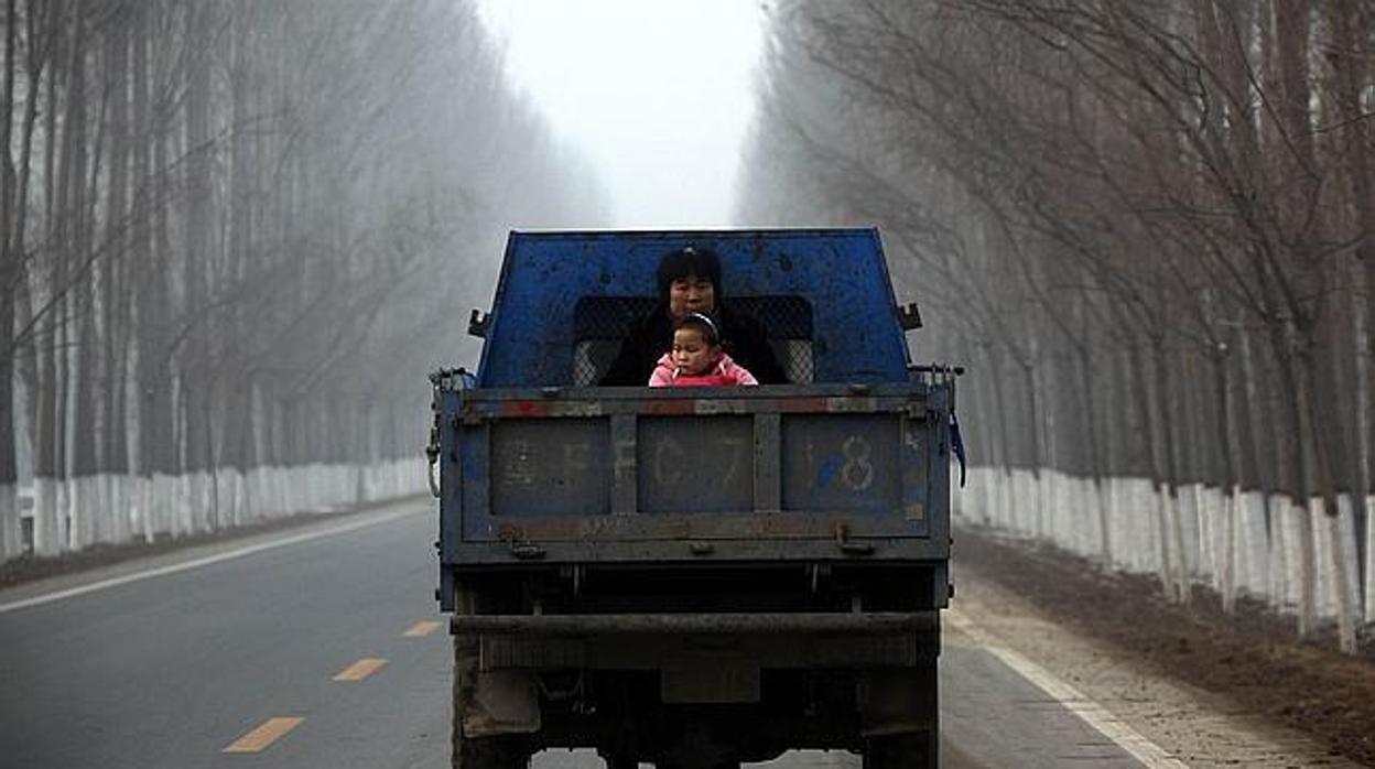 Una mujer, junto a su hija en la parte trasera de una furgoneta en Pekín