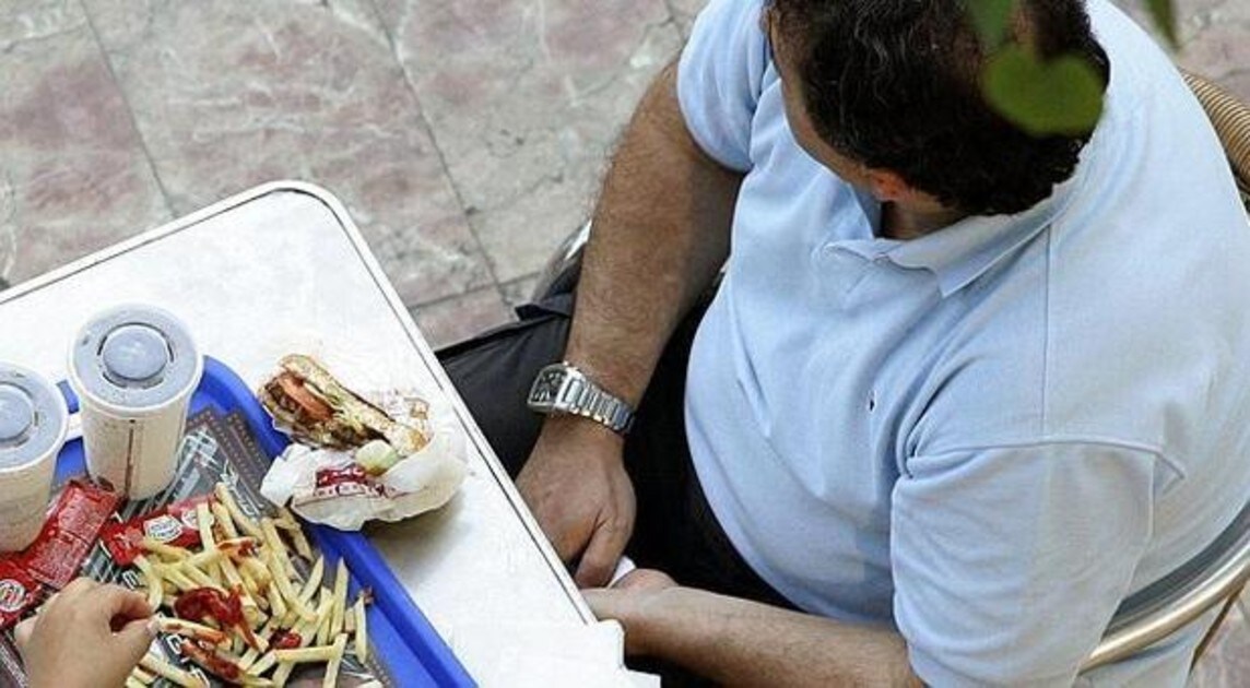 Un hombre consume comida basura en un restaurante