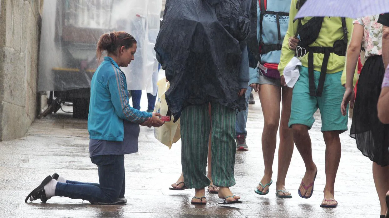 Mujer embarazada pidiendo en la calle bajo la lluvia