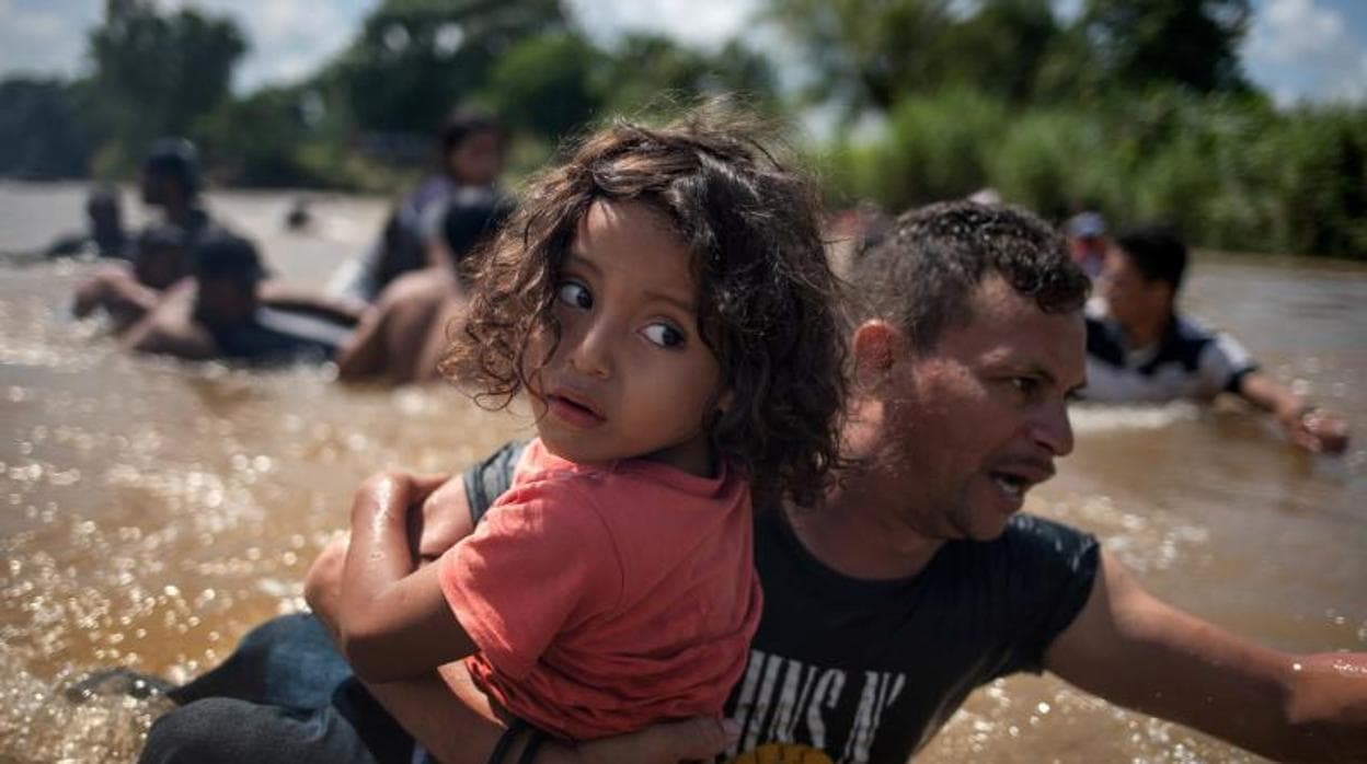 Una niña, inmigrante de Honduras, en brazos de su padre, cruza el río Suchiate, frontera entre Guatelama y México