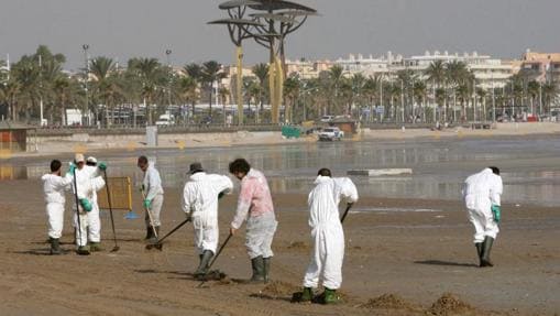 Operarios de Repsol limpian la playa de La Pineda