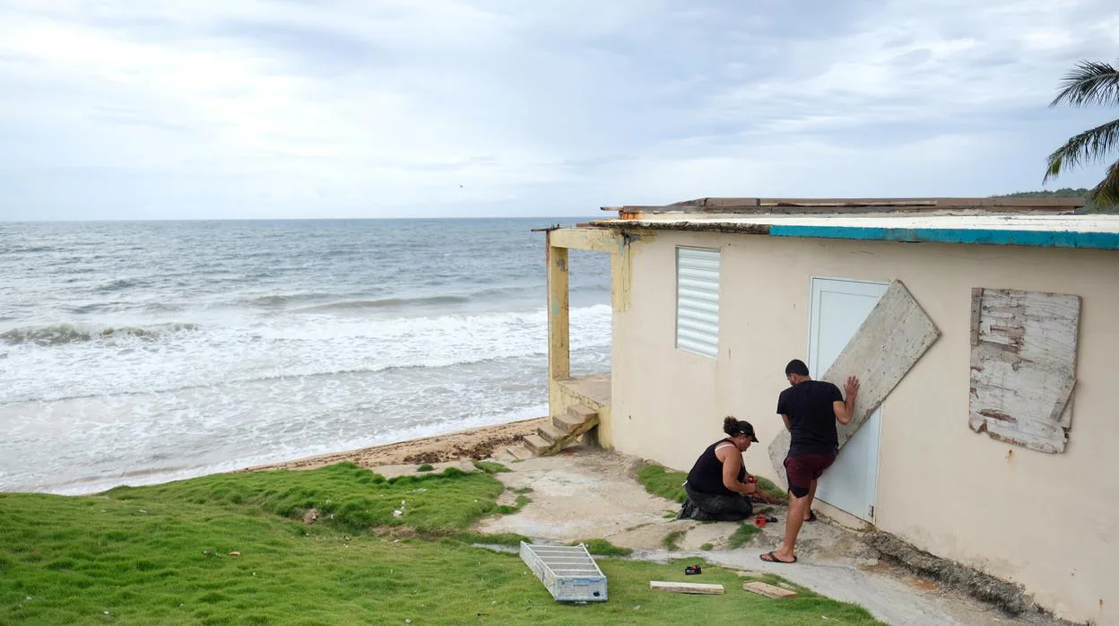 Dos personas refuerzan puertas y ventanas de su casa ante la llegada de la tormenta tropical Dorian a Yabucoa, en Puerto Rico