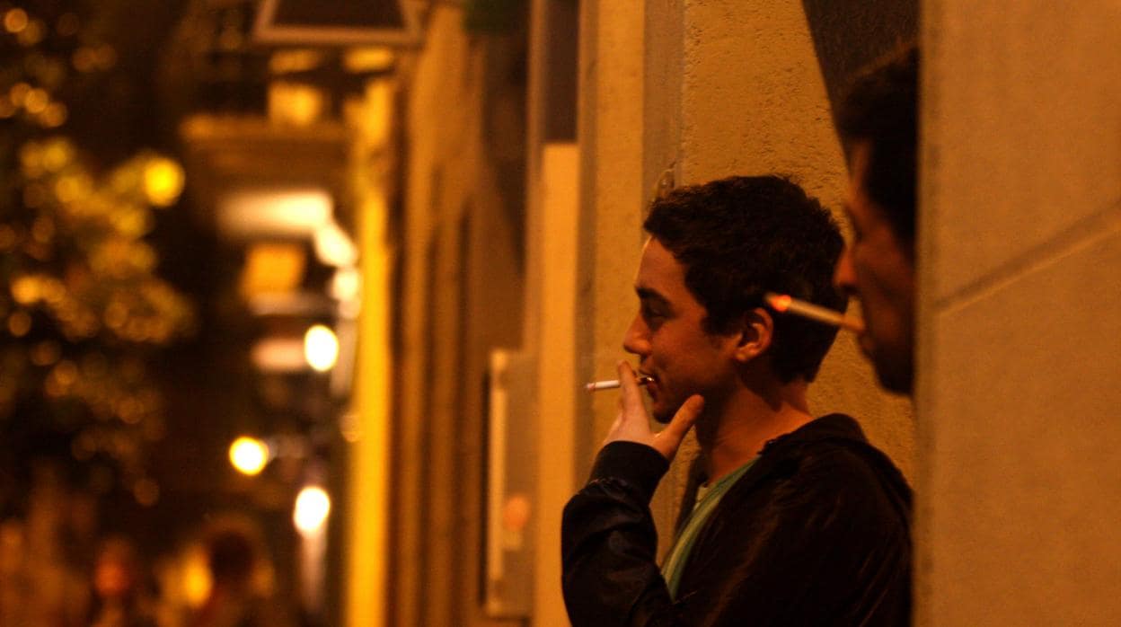 Jóvenes fumando a la salida de un bar