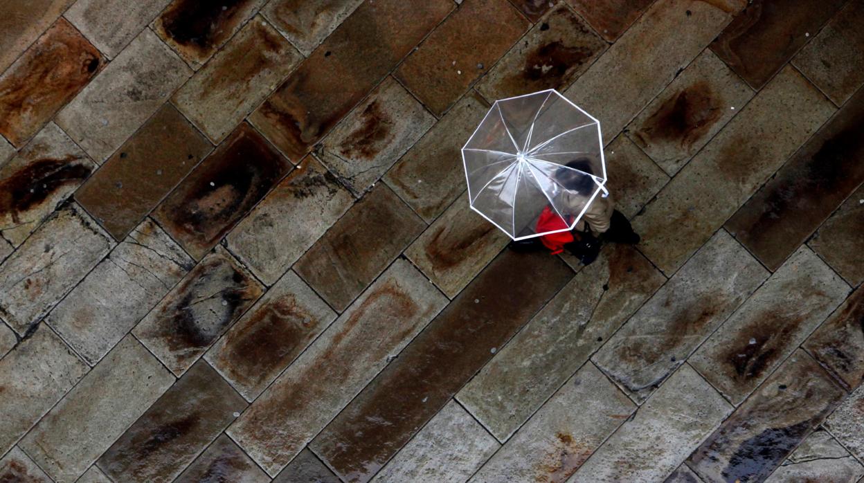 Una mujer camina bajo la lluvia en la calle Real de La Coruña