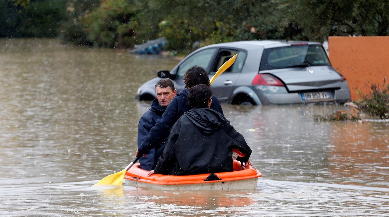 Unas personas usan una canoa en medio de calles sumergidas debido a las fuertes lluvias en Le Muy (Francia)