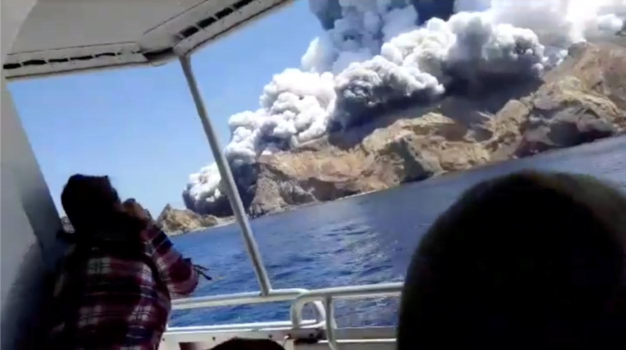 Un turista fotografía el volcán Whakaari en un barco