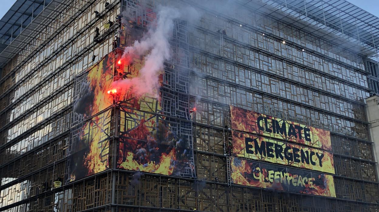 Los bomberos retiran en Bruselas una pancarta de Greenpeace mientras el Consejo Europeo debate su plan verde