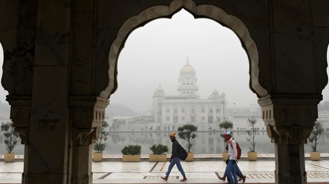 Los devotos caminan alrededor del Gurudwara Bangla Sahib en condiciones de mucha niebla en Nueva Delhi