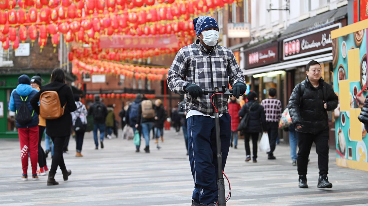 Un hombre va en patinete con mascarilla por calles de Londres