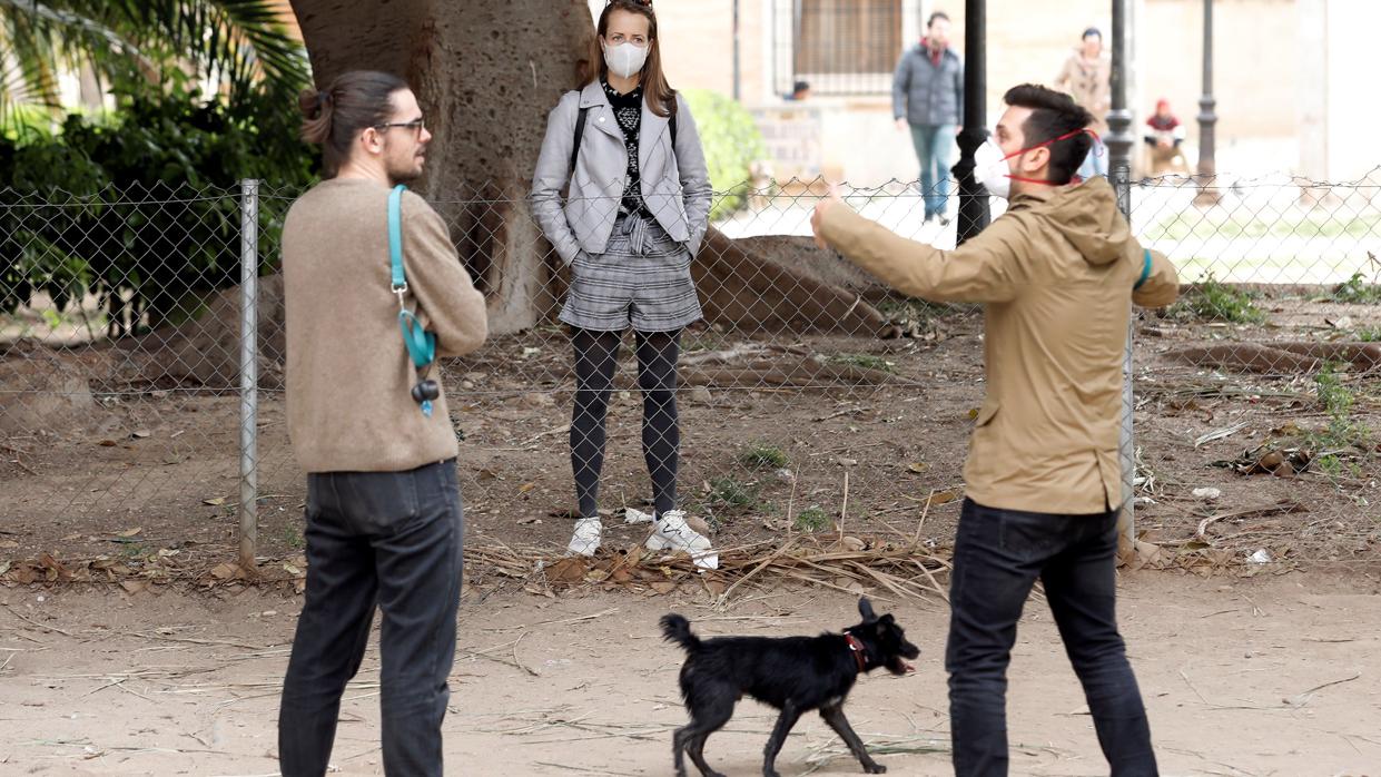 Una mujer protegida con mascarilla pasea a su mascota, hoy en Valencia, tras entrar en vigor el estado de alarma decretado por el Gobierno