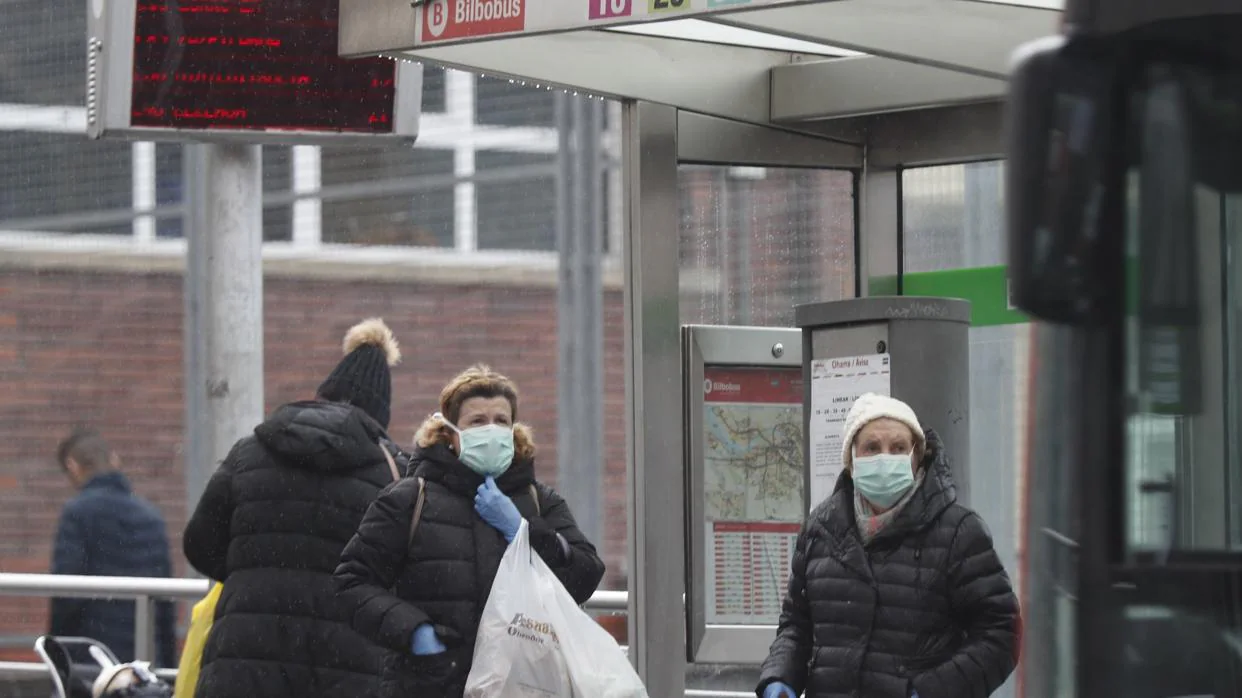Coronavirus: Dos mujeres con mascarilla esperan a un autobús urbano en Bilbao