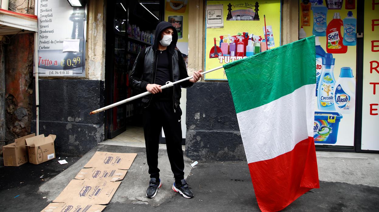 Un hombre frente a una tienda con una bandera italiana