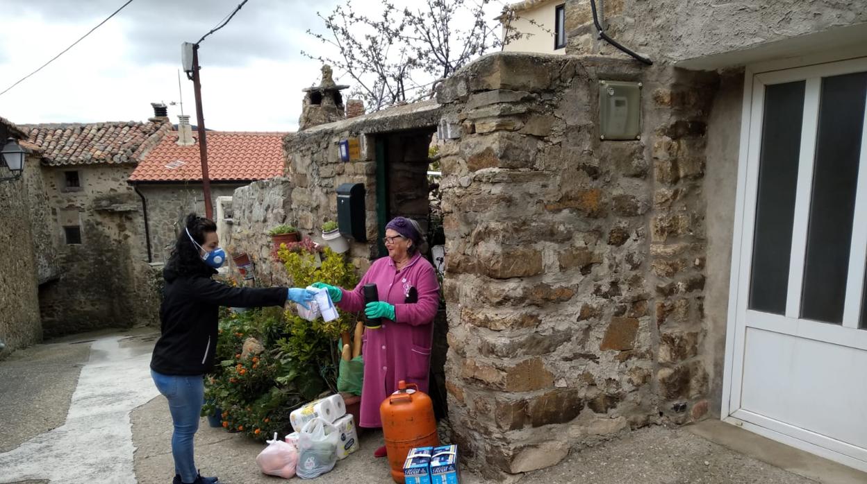 Lali Cabriada (i) entrega a Nati Domínguez (d) la compra semanal en su casa de Valtajeros, un pueblo de 25 habitantes de Soria