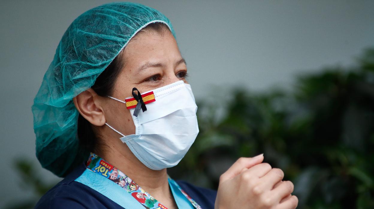 Una sanitaria, con una mascarilla que muestra una bandera de España con un lazo negro de luto por los fallecidos por coronavirus