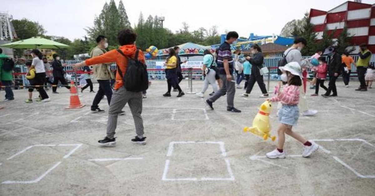 La gente mantiene la distancia de seguridad mientras esperan para entrar a un parque de atracciones en Seúl