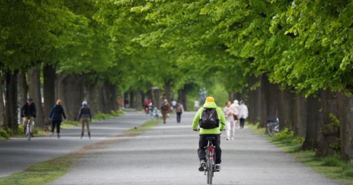 Un grupo de ciclistas y viandantes pasean por un parque en Hannover (Alemania)