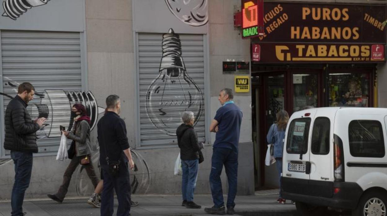 Varias personas hacen cola en un estanco en el centro de Madrid