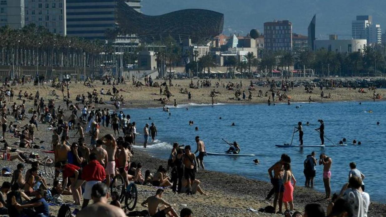 Gente tomando el sol en la playa de la Barceloneta, en Barcelona, este 20 de mayo