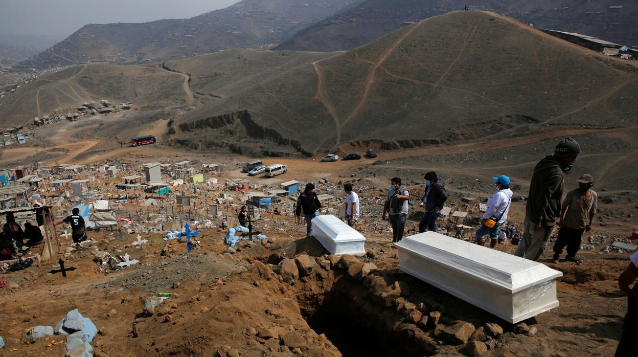 Dos familias junto a los ataúdes de sus seres queridos en un cementerio de Lima, Perú