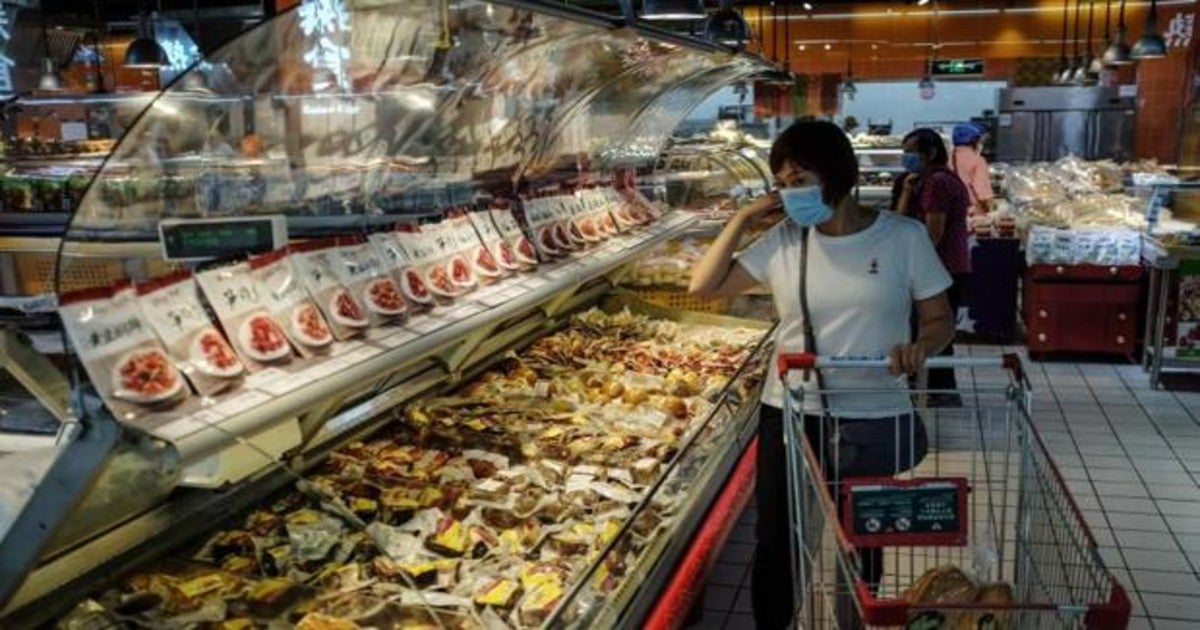 Una mujer con mascarilla hace la compra en el mercado de Pekín donde se produjo el rebrote