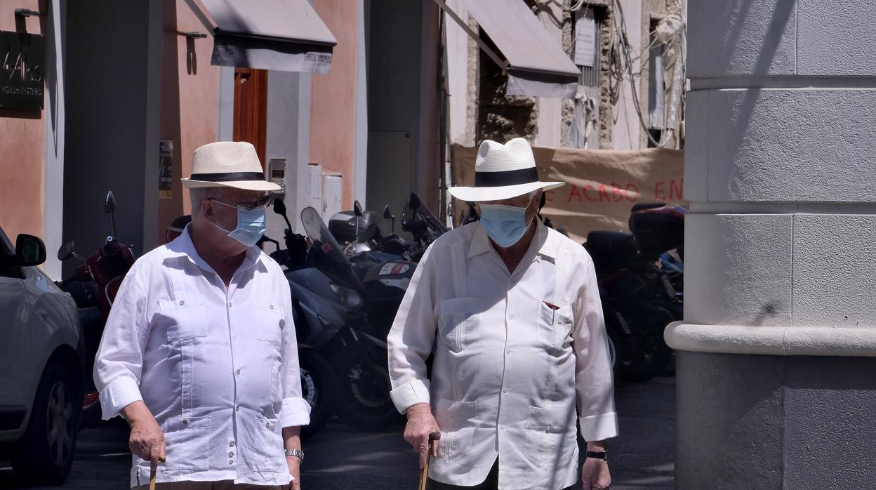 Dos hombres pasean por Sevilla con la mascarilla puesta