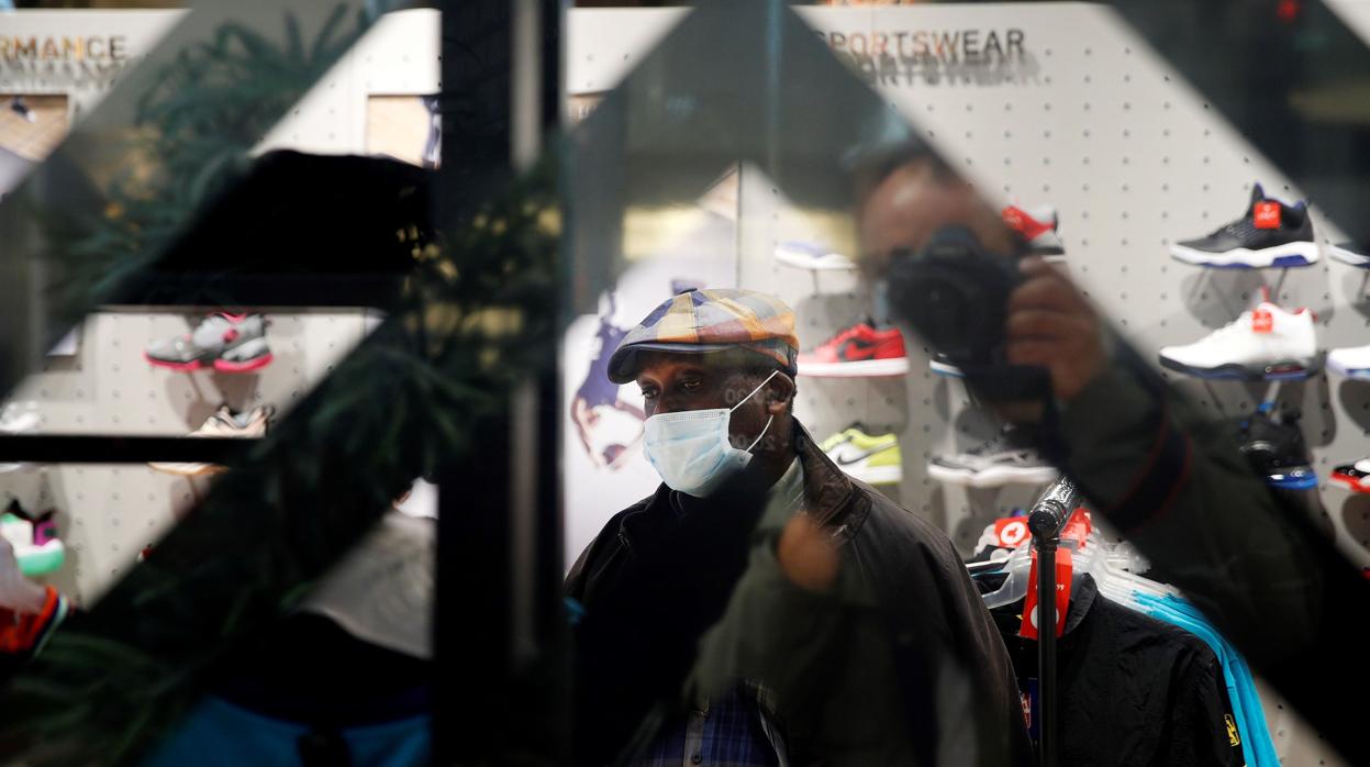 Un hombre protegido con una mascarilla realiza compras en los Campos Elíseos en París, ayer