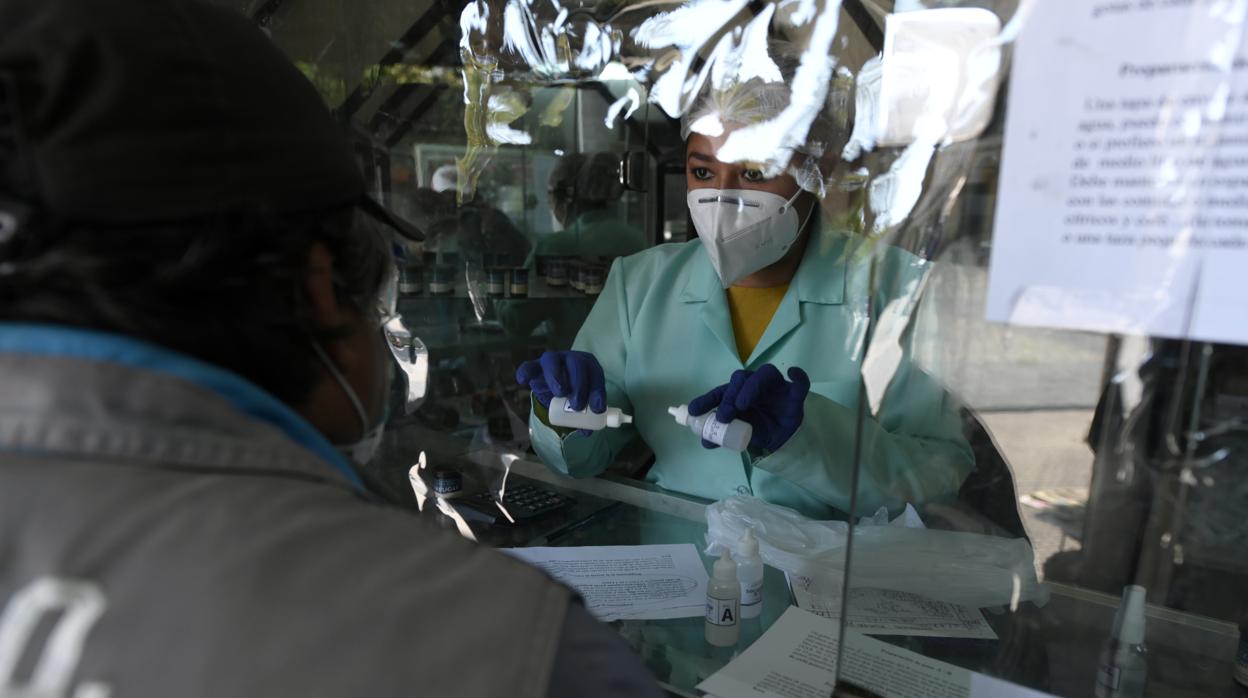 Un farmacéutico le da instrucciones a un cliente sobre cómo usar un medicamento que contiene dióxido de cloro en Cochabamba, Bolivia