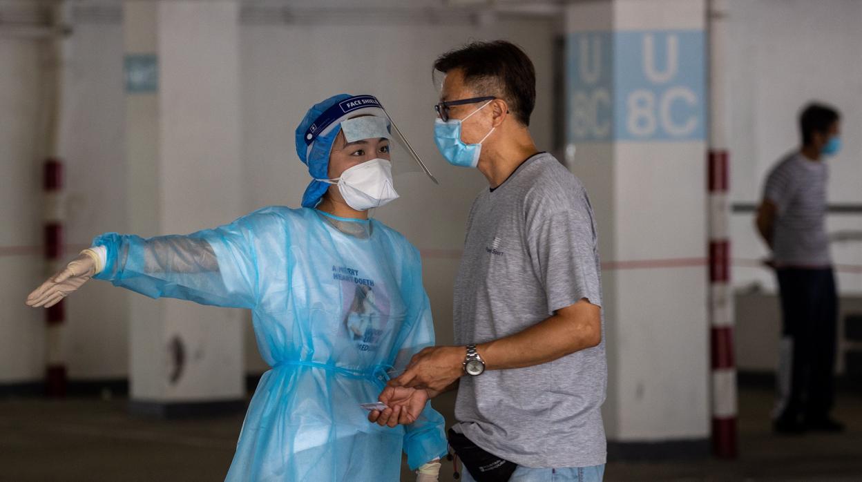 Una sanitaria dirige a un taxista a un laboratorio de test Covid improvisado en un aparcamiento de Hong Kong