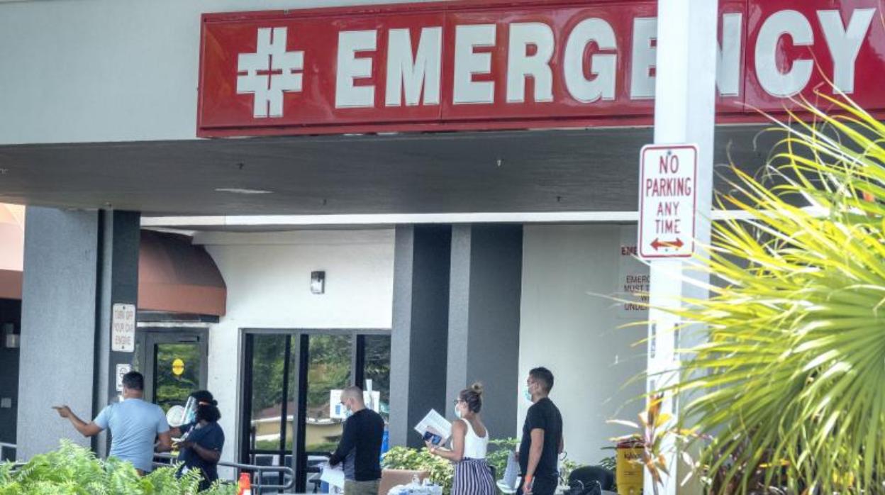 Un grupo de personas con mascarillas espera en las puertas de un hospital en EE.UU.