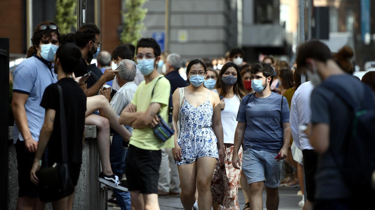 Varias personas caminan con mascarilla por una calle del centro de Madrid