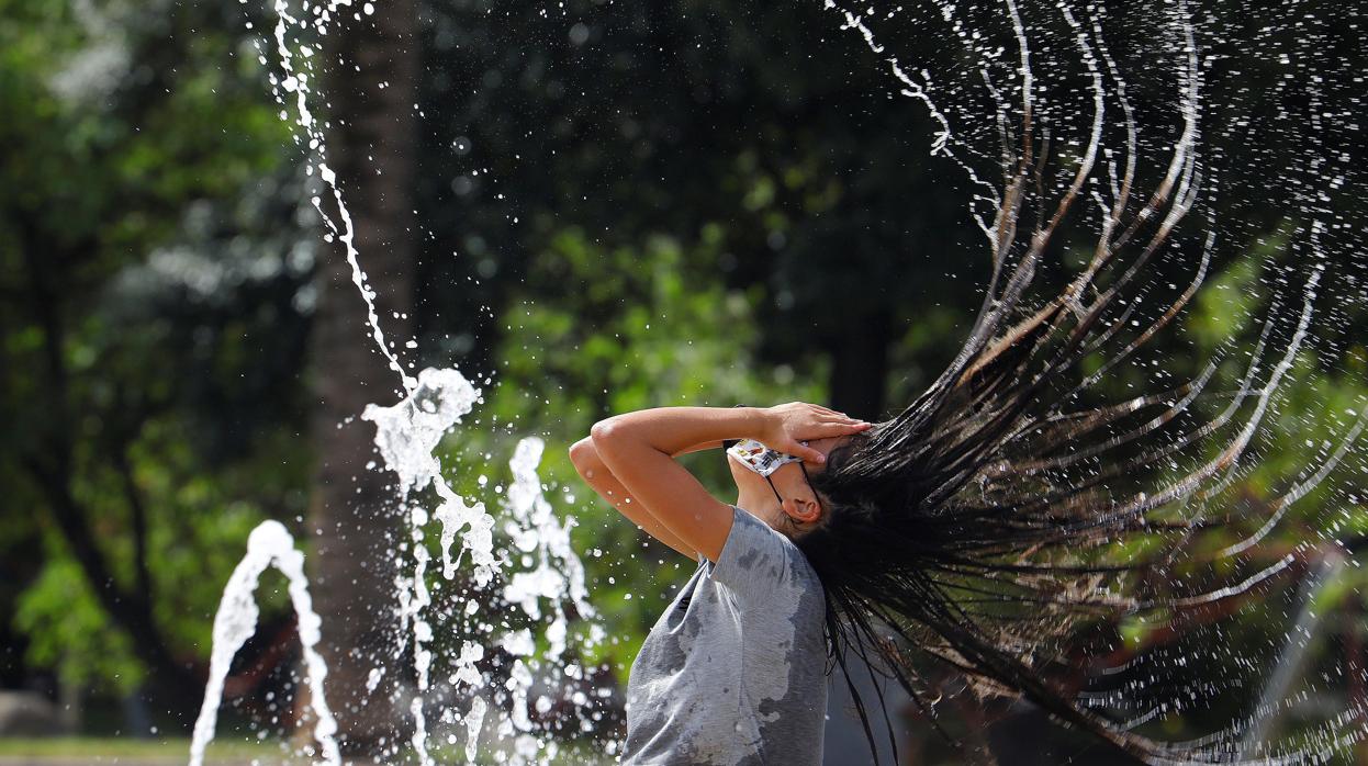 Una joven se refresca en una fuente de Córdoba