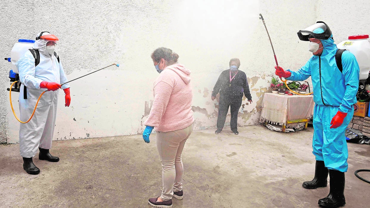 Operarios desinfectan a una mujer en Xochimilco (México) como medida preventiva frente al coronavirus