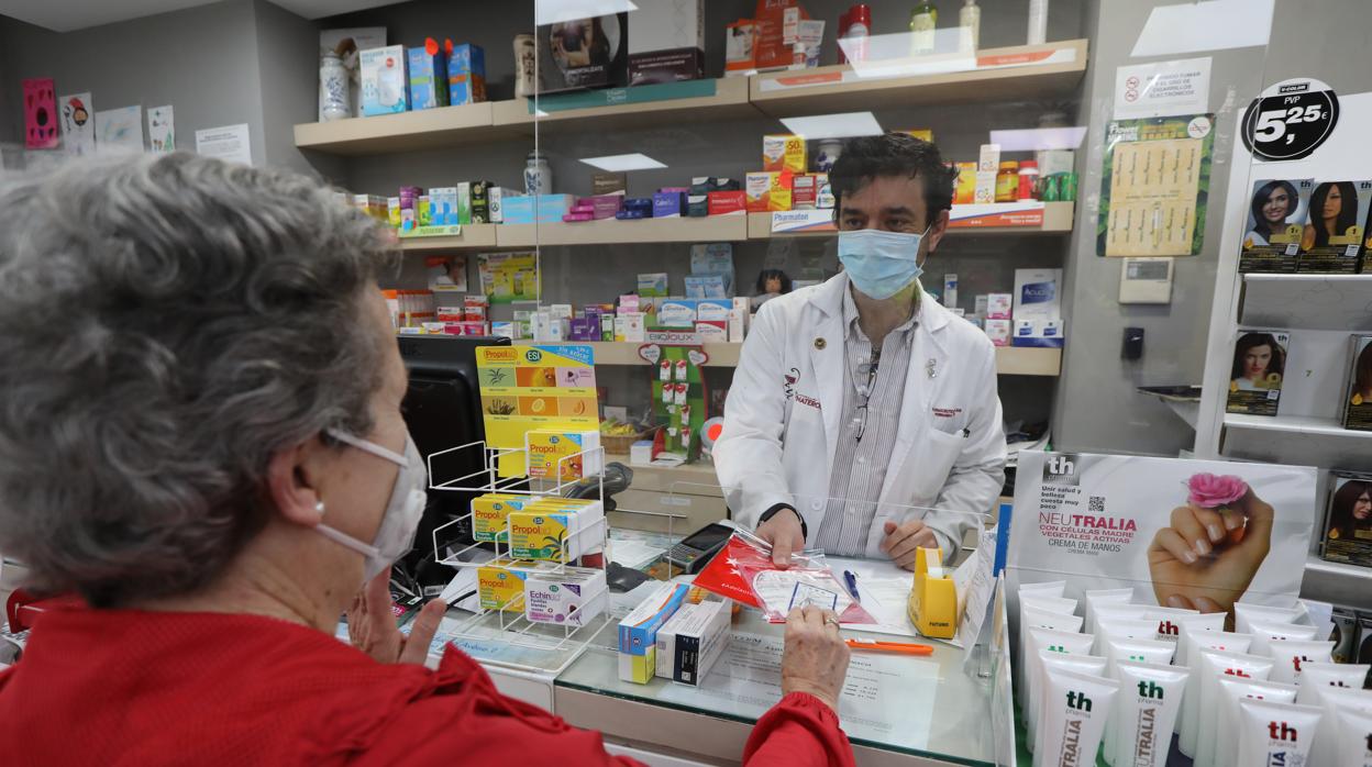 Un farmaceútico entrega a una clienta una mascarilla KN95