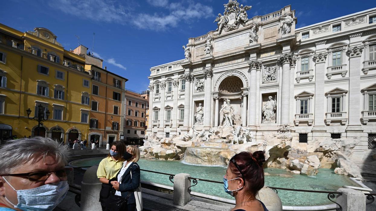 Un grupo de turistas con mascarilla en la Fontana di Trevi, en Roma