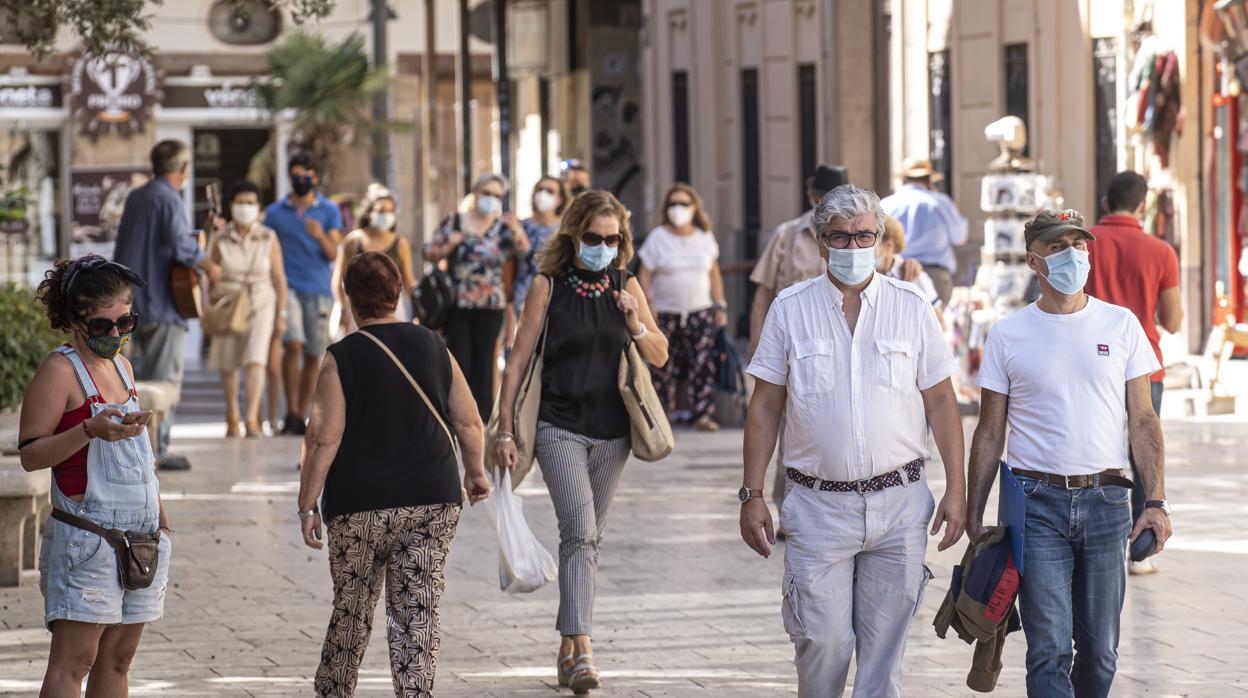 Un grupo de viandantes con mascarilla pasea por las calles de Valencia