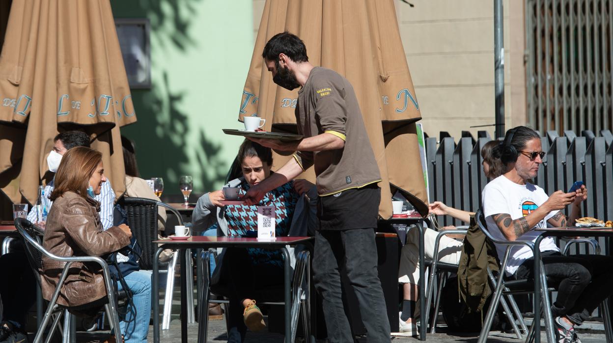 Un camarero sirve a unas clientas en una terraza de un bar de Barcelona