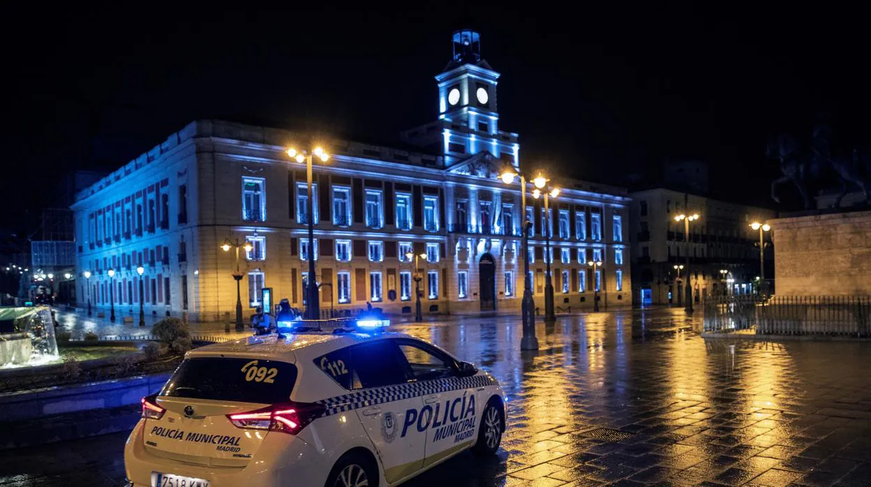 Un coche de la Policía Local vigila la Puerta del Sol anoche, rimera jornada de toque de queda en la capital