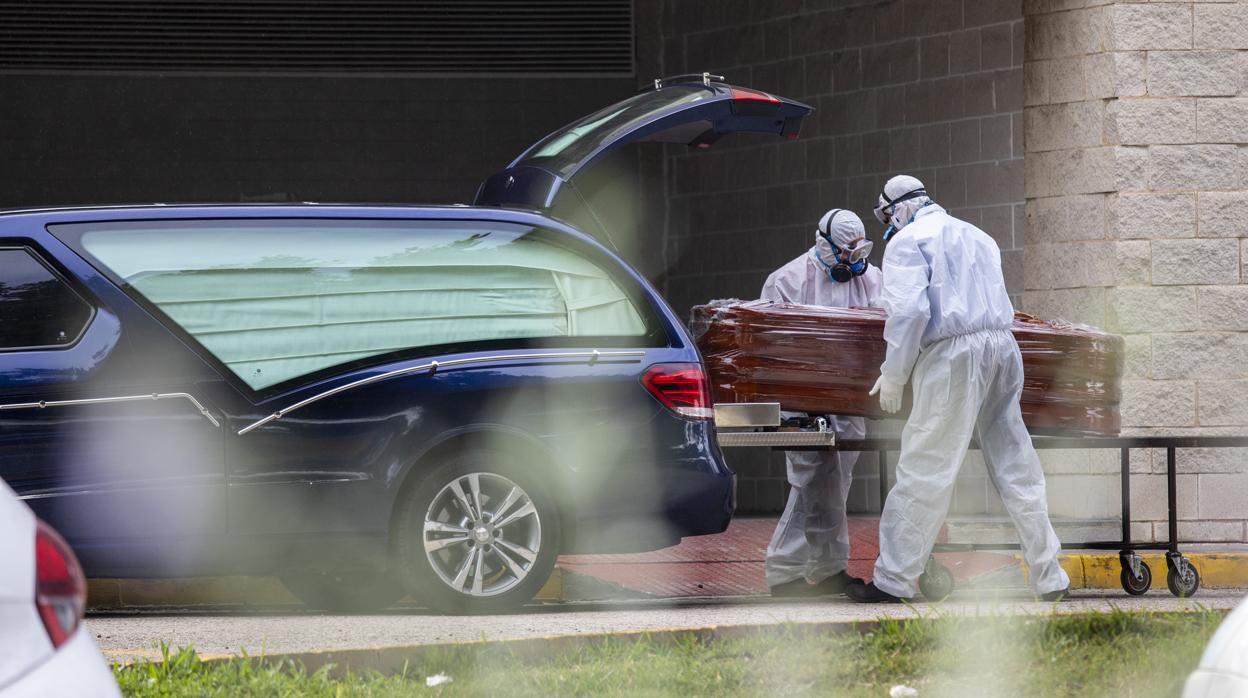 Operarios del tanatorio trasladan a un fallecido por coronavirus del mortuorio Hospital Juan Ramón Jiménez de Huelva