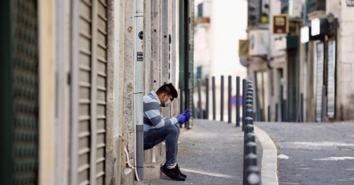 Un joven , con guantes y mascarilla, en el barrio de Alfama en Lisboa