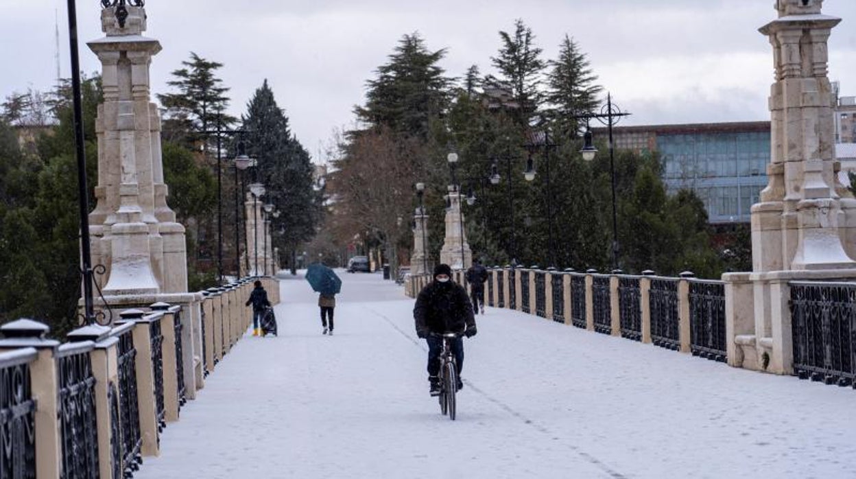 Un hombre pasea con su bicicleta por las calles nevadas de Teruel