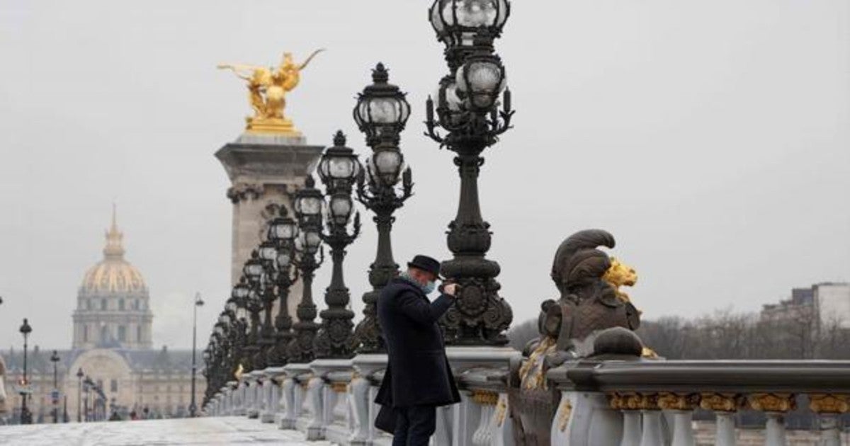 Un hombre toma una fotografía del río Sena sobre el puente de Alexandre III