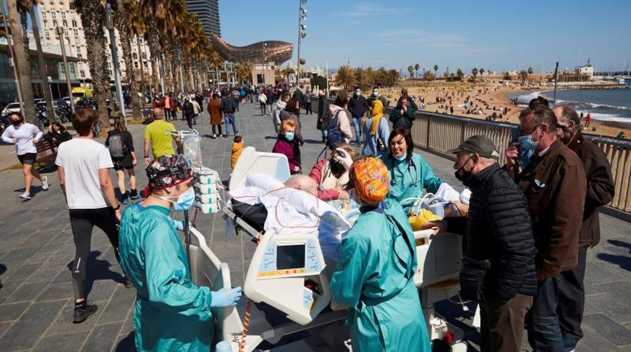 Un paciente con Covid-19 de 63 años, ingresado en el Hospital del Mar, sale al paseo marítimo acompañado por varios sanitarios en Barcelona