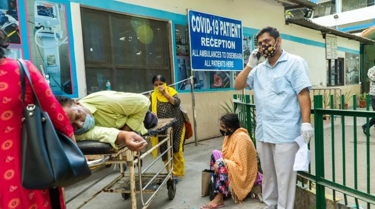 Un paciente espera en una camilla rodeado de sus familaires para ser admitido en un hospital