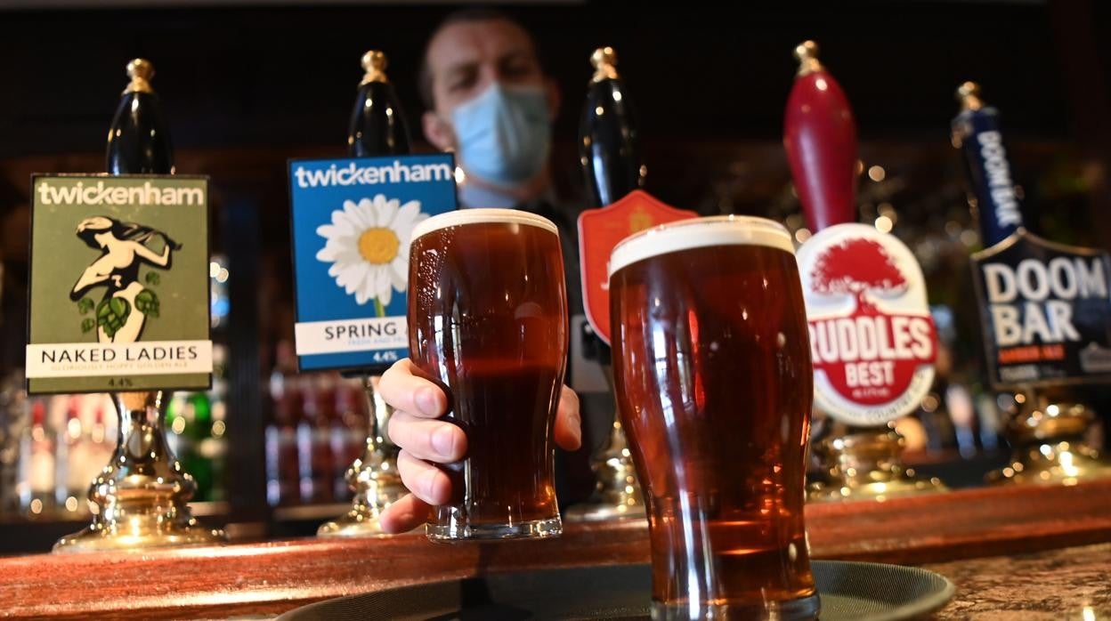 Un camarero sirviendo dos pintas en un bar de Londres