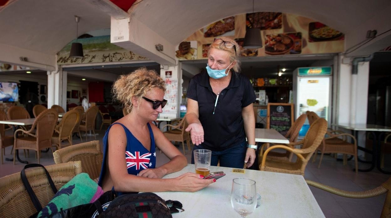 Una camarera balear conversa con una turista británica en Palma de Mallorca, durante el verano de 2020